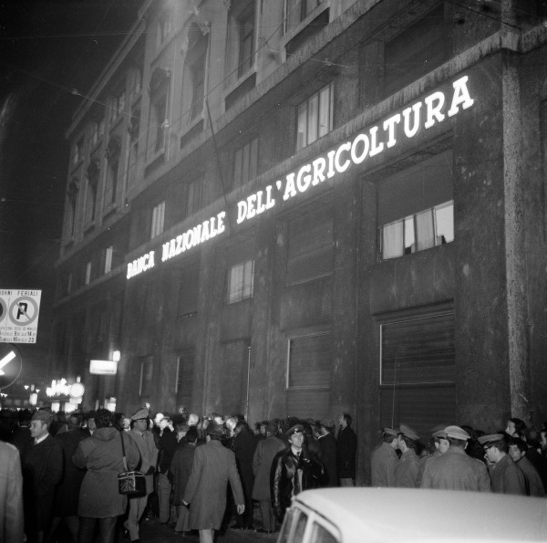 Forze dell'ordine, giornalisti e cittadini davanti alla Banca Nazionale dell'Agricoltura, in piazza Fontana a Milano, il giorno della strage, 12 dicembre 1969. Archivio Storico Intesa Sanpaolo, Archivio Publifoto